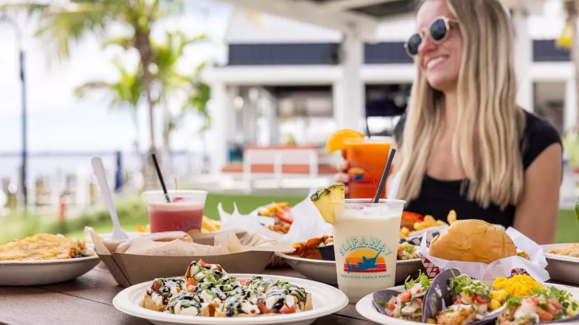 Smiling woman with cocktail and plates of food